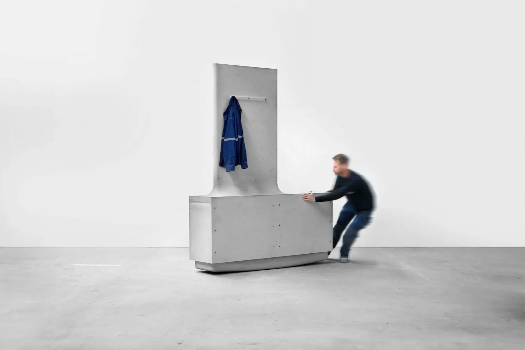 Person pushing a movable concrete module from MIT’s Heirloom House project, demonstrating the manually rearrangeable structural components designed by Matter Design and Cemex