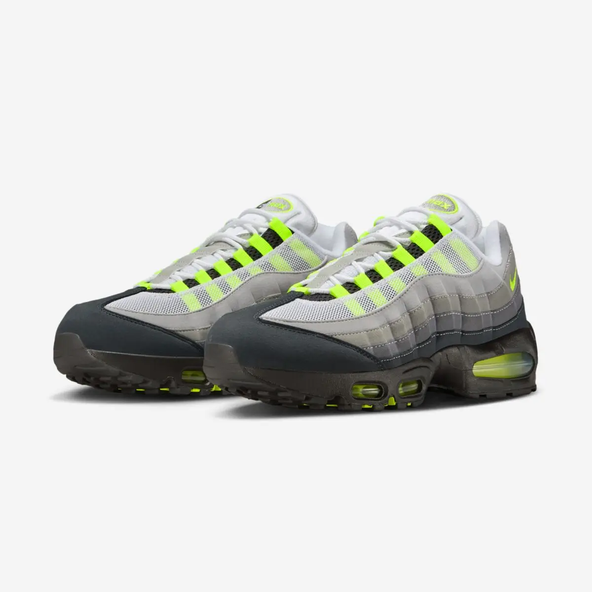 Angled front-side view of the Nike Air Max 95 OG “Neon” 2026 pair, featuring the signature grey gradient upper, black mudguard, volt lace loops and Swoosh, and enlarged visible Air units in the heel and forefoot