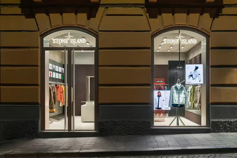 Minimalist exterior of the Stone Island flagship store in Naples, showing clean architectural columns, neutral tones, and curated technical apparel displays within the retail space