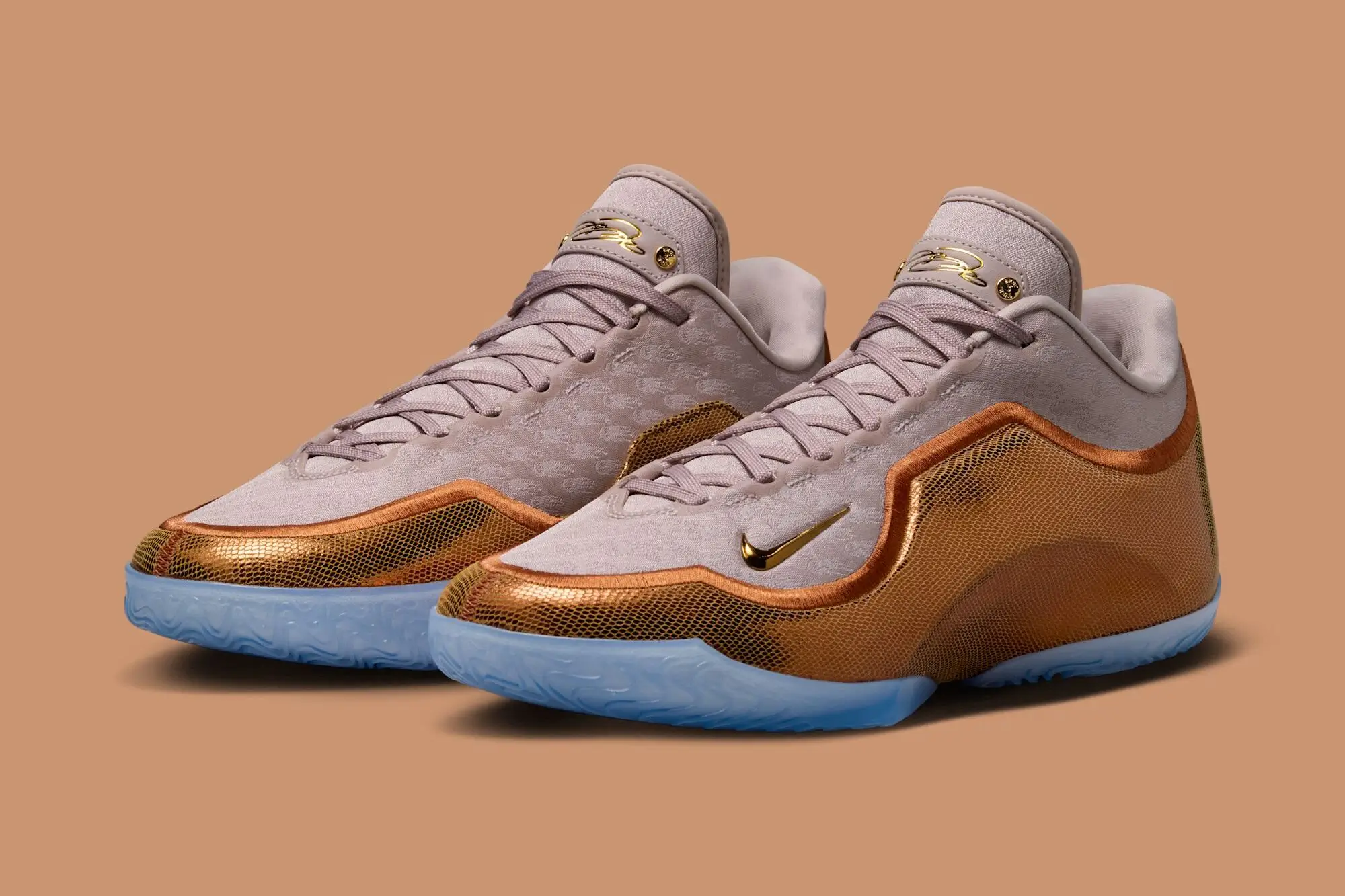 Nike LeBron 23 “LeBronto” basketball sneakers in beige suede and metallic amber mesh with gold Swoosh logos and translucent icy blue outsoles, shown in an angled pair view