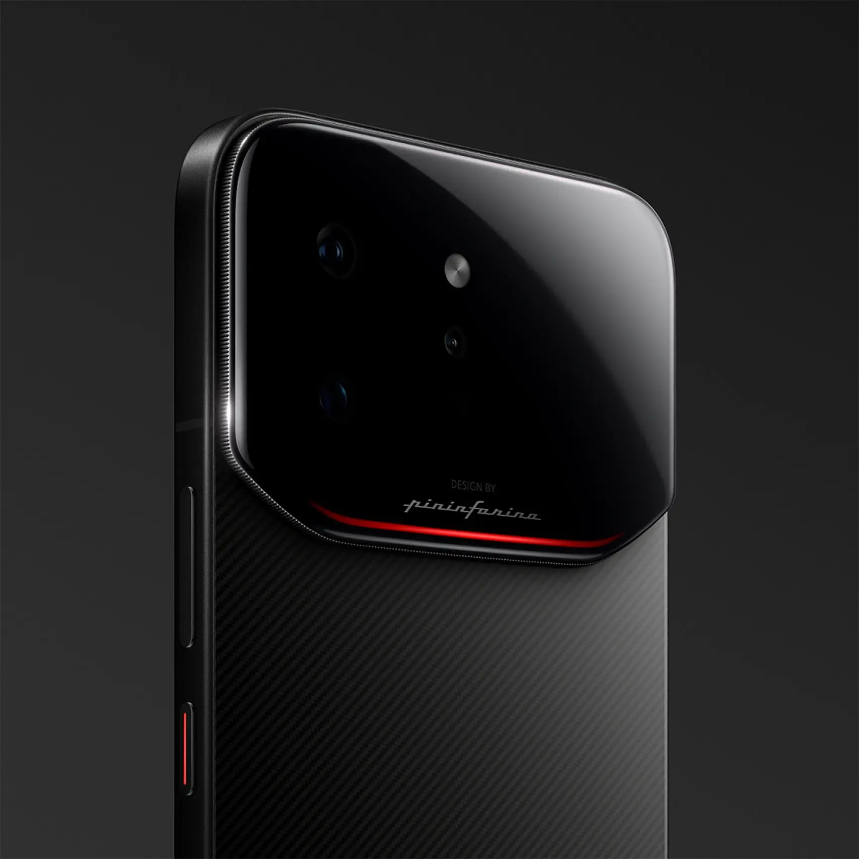 Close-up of the Infinix Note 60 Ultra smartphone designed with Pininfarina, showing the upper rear section in a matte black carbon-fiber-style finish. A large, glossy black camera module with rounded corners houses multiple lenses and sensors, accented by a thin red line beneath it. The “Design by Pininfarina” script is visible below the camera module. The side frame features a slim profile with a textured edge and a red-accented button, while soft lighting highlights the premium materials and automotive-inspired detailing