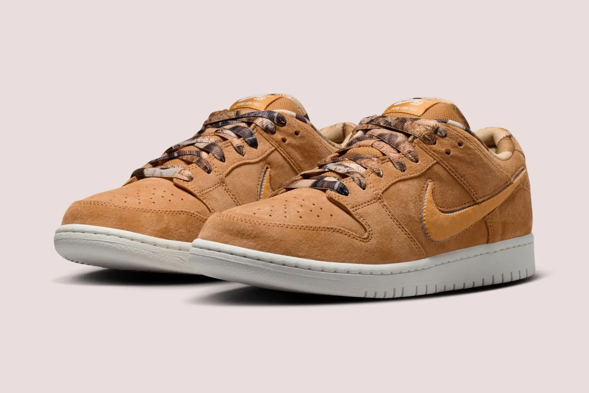 Angled pair view of NOTE x Nike SB Dunk Low “Brew & Biscuits” in biscuit-brown suede with tonal Swoosh, marbled coffee-toned laces, perforated toe box, and off-white sole, emphasizing layered textures and warm neutral palette