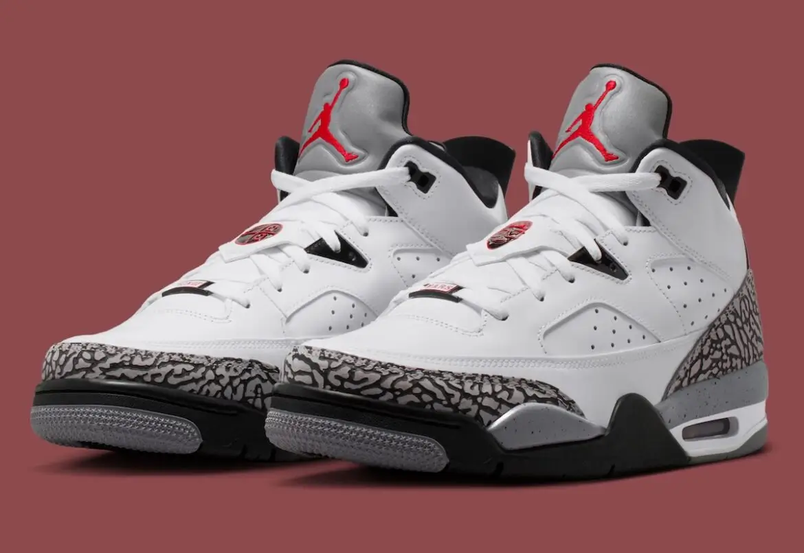 Pair of Jordan Son of Mars “White Cement” sneakers in angled front view featuring white leather uppers, grey elephant print mudguards, black midsoles, visible Air units, and red Jumpman branding