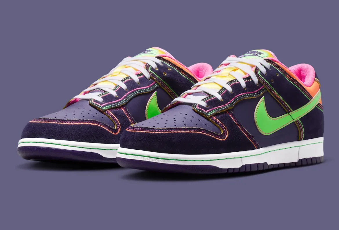 Angled front view of the Nike Dunk Low “Dynasty Purple” featuring a deep purple leather base with dark suede overlays, multicolor contrast stitching, bright green Swoosh, pink lining, yellow tongue, and white midsole with purple outsole