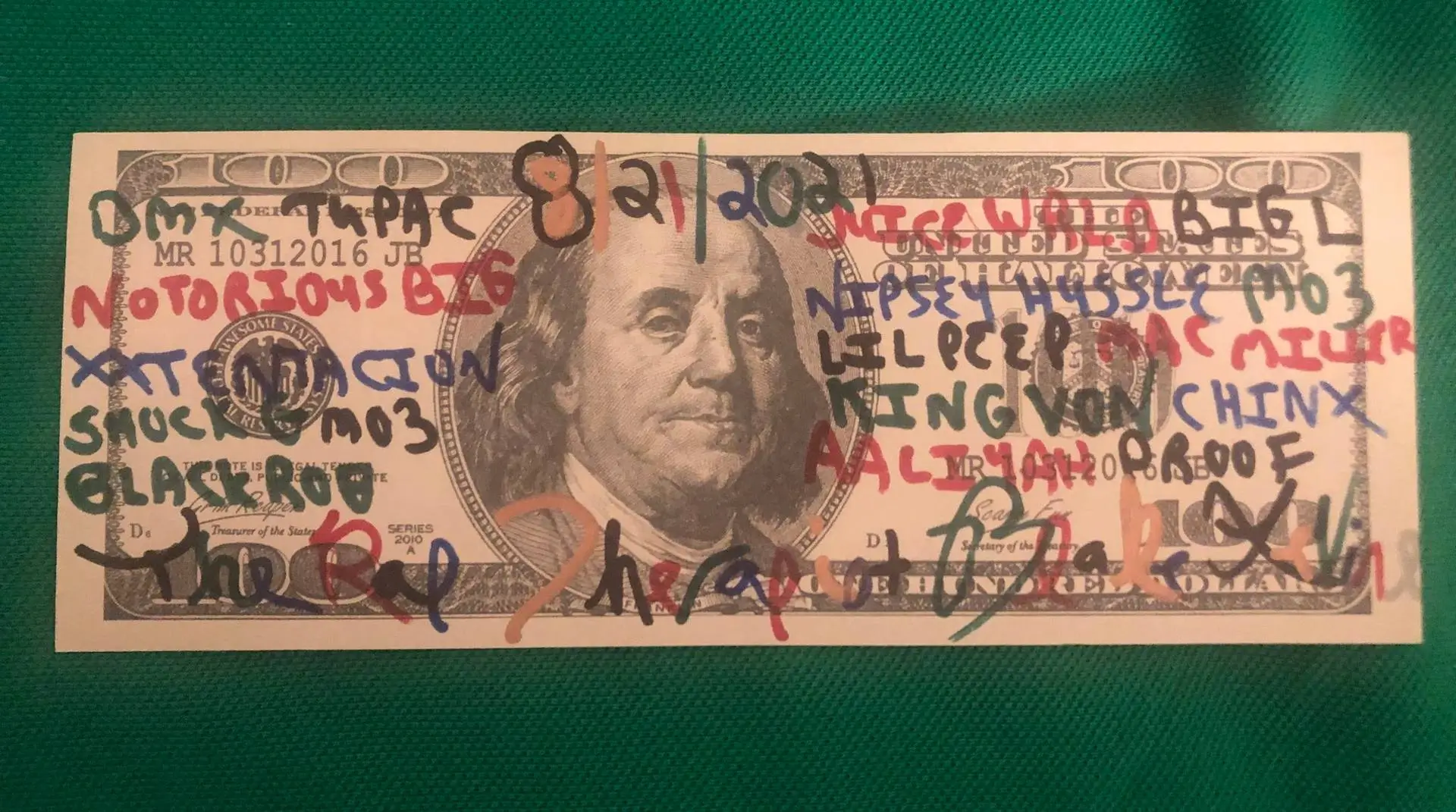 Hand-drawn reinterpretation of a U.S. hundred-dollar bill on paper, featuring Benjamin Franklin’s portrait overlaid with colorful marker graffiti listing hip-hop artists’ names such as Tupac, Notorious B.I.G., Nipsey Hussle, and Lil Peep, set against a green textured background