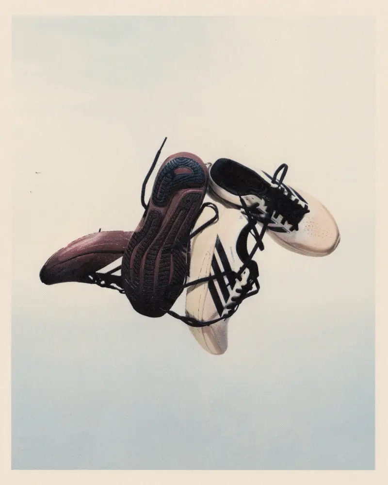 Song for the Mute x adidas Running SS26 sneakers suspended mid-air, featuring a deconstructed black-and-white upper with exposed lacing and a textured, sculptural outsole against a soft neutral background