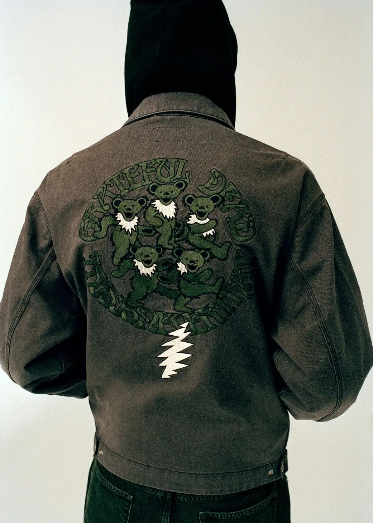 thisisneverthat® × Grateful Dead jacket back view with tonal dancing bears circle graphic and white lightning bolt on a washed dark outerwear silhouette
