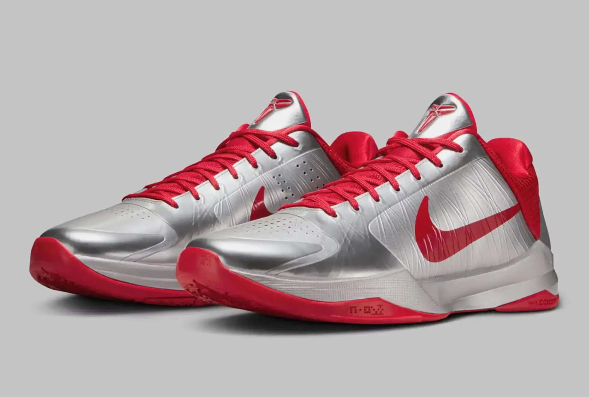 Metallic silver Nike Kobe 5 Protro sneakers featuring bold red Swooshes, red laces, and matching outsole, shown in a clean studio setup with low-cut performance silhouette and streamlined paneling