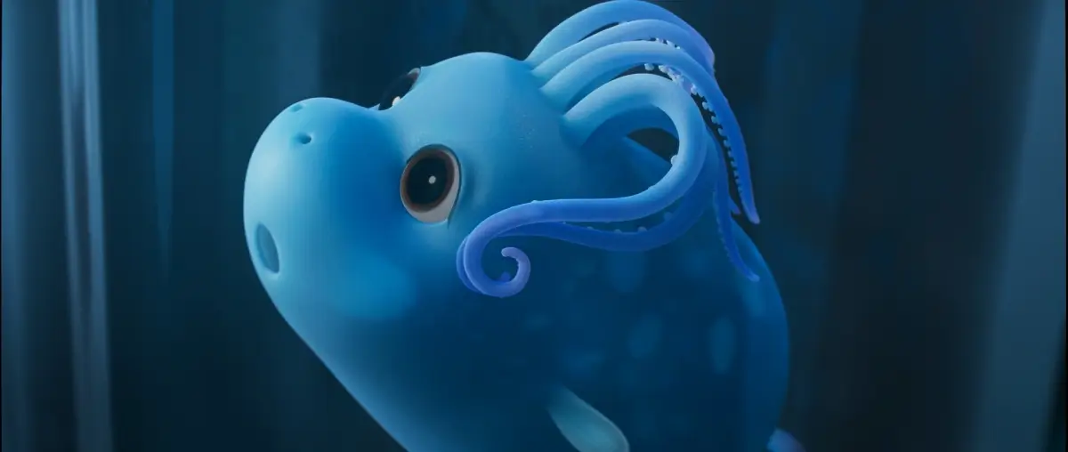 Piglet squid character from Ally by Bong Joon Ho, rendered as a soft blue animated creature with rounded features and large expressive eyes, floating underwater with curled tentacles in a dimly lit deep-sea environment