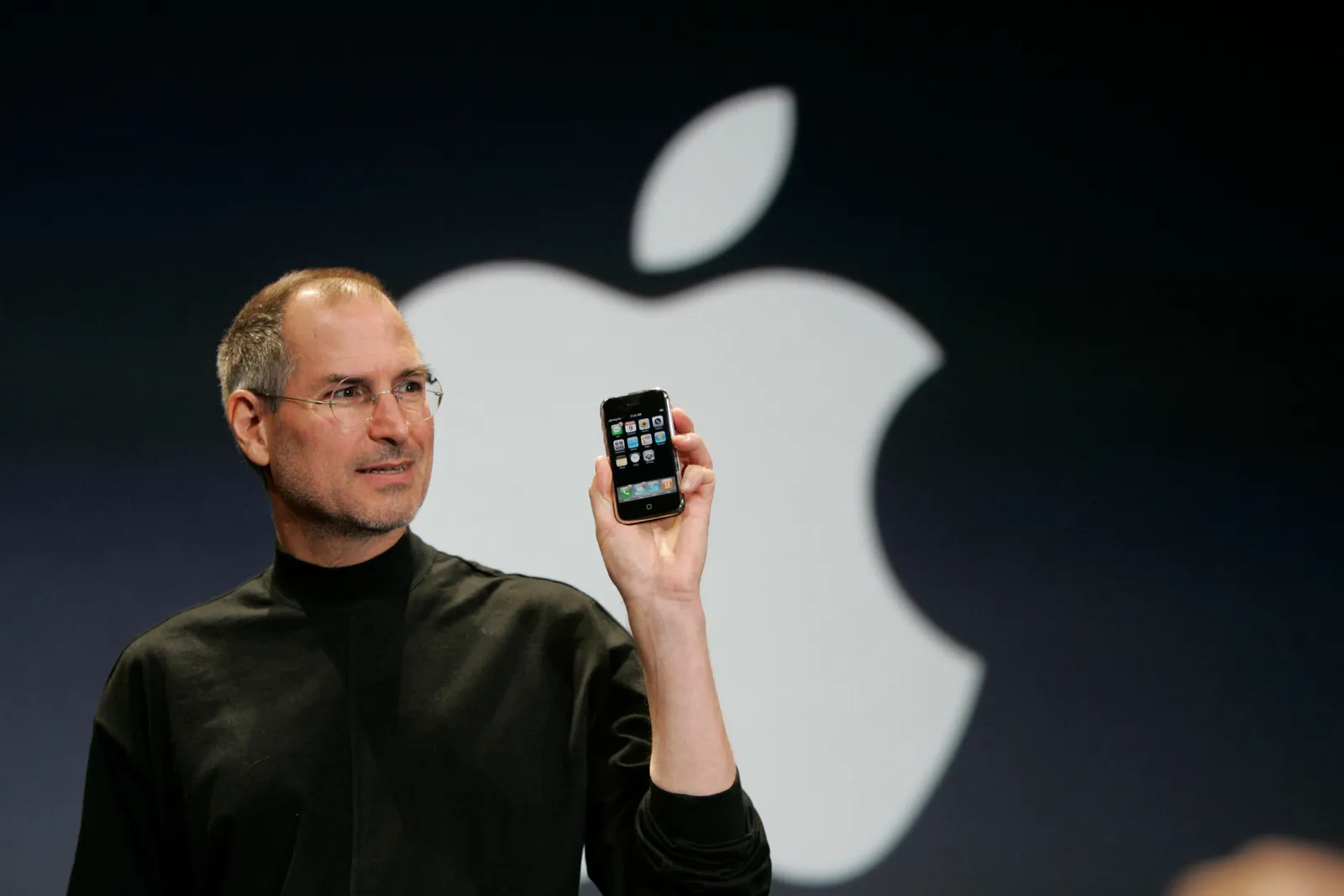 Steve Jobs presenting the original iPhone on stage with Apple logo backdrop