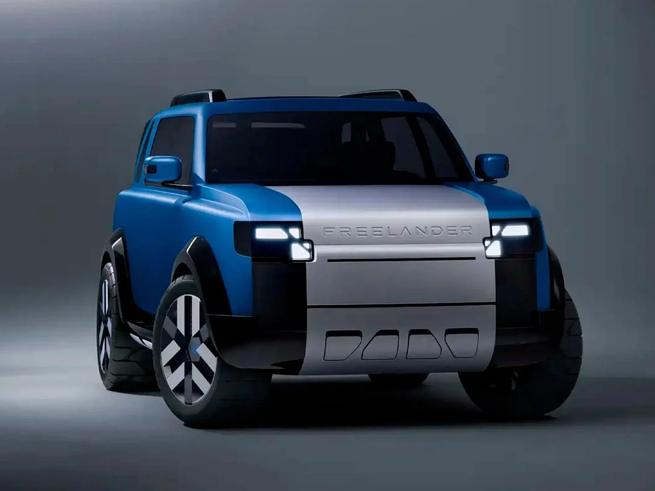 Front three-quarter view of the Freelander Concept 97 electric SUV in blue with a contrasting silver front panel, squared LED headlights, bold wheel arches, and a compact, boxy stance that blends modern EV design with off-road-inspired proportions