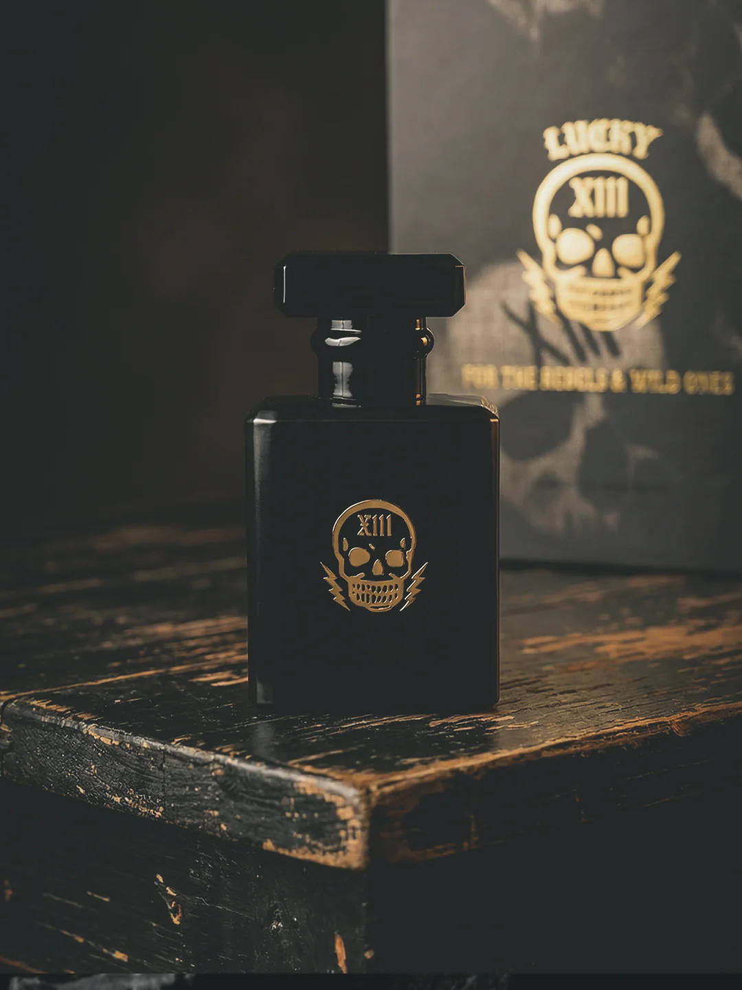 Lucky XIII fragrance bottle by Sun City Rags in matte black glass with gold skull XIII emblem, placed on a worn wooden surface under warm, low lighting