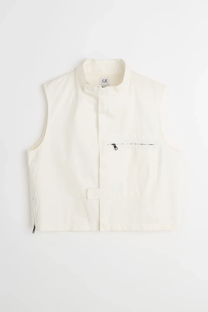 White C.P. Company 1990s cloth fabric utility gilet front view featuring a stand collar with Velcro tab, concealed closure, asymmetric chest zip pocket, and structured cropped silhouette
