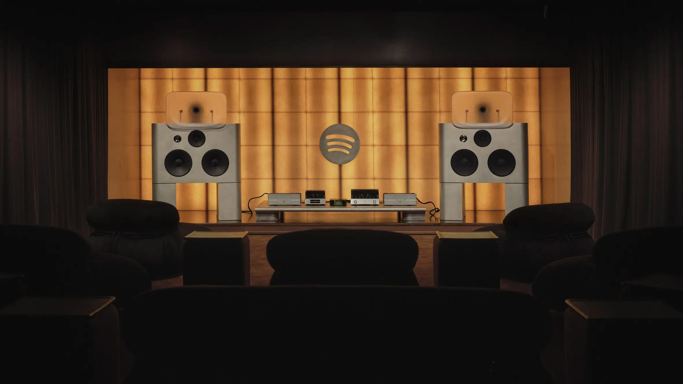 Spotify Listening Lounge London with dual custom speakers, warm backlit acoustic wall panels, and a centered high-fidelity audio system setup