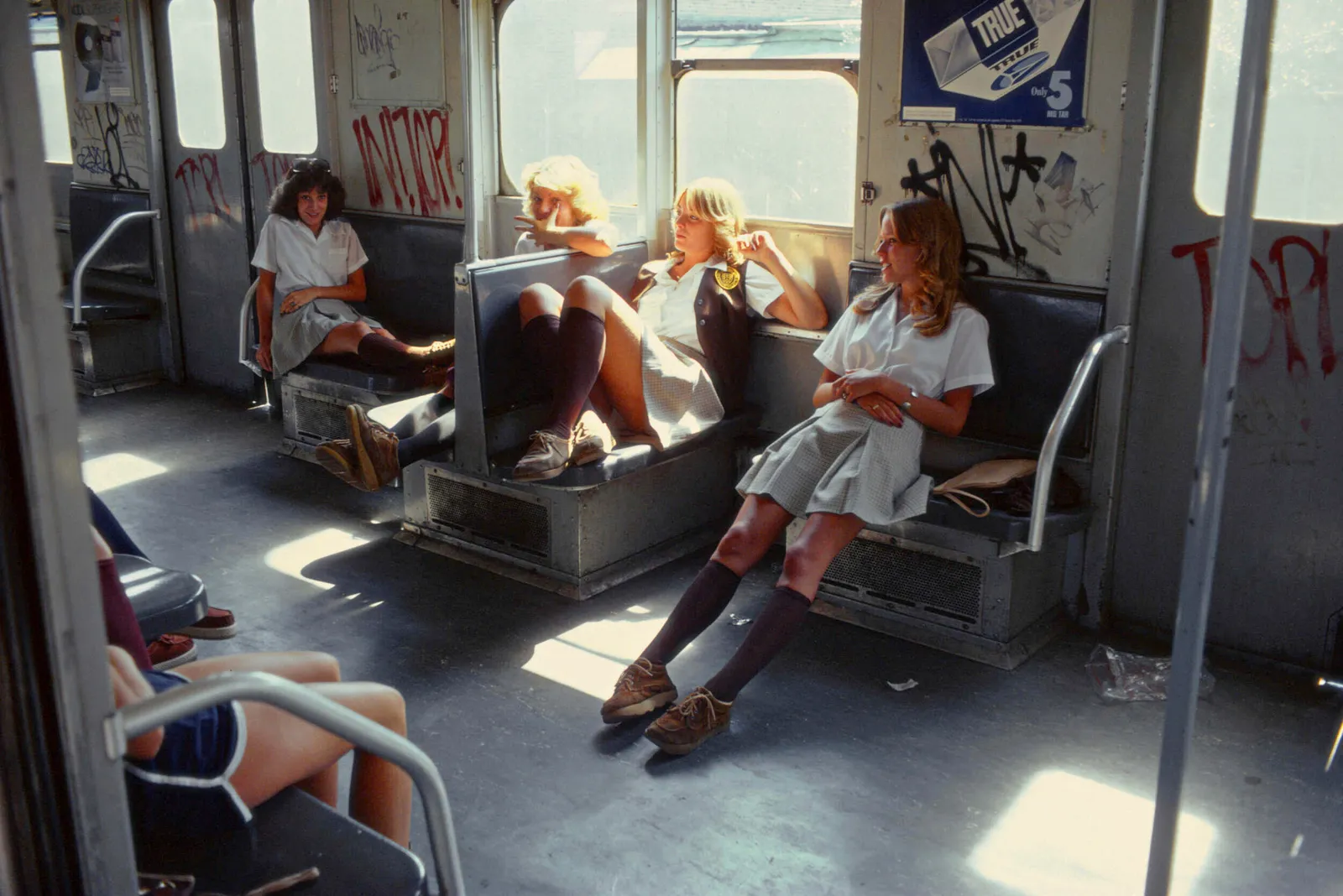 Schoolgirls in uniform lounge across subway seats on a sunlit A train to Far Rockaway, New York, 1978, photographed by Willy Spiller, capturing a candid moment of youth in transit