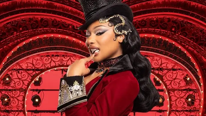 Portrait of Megan Thee Stallion in a red cabaret-style costume with a black top hat and jeweled accessories, posed against an ornate red stage backdrop inspired by Moulin Rouge! The Musical