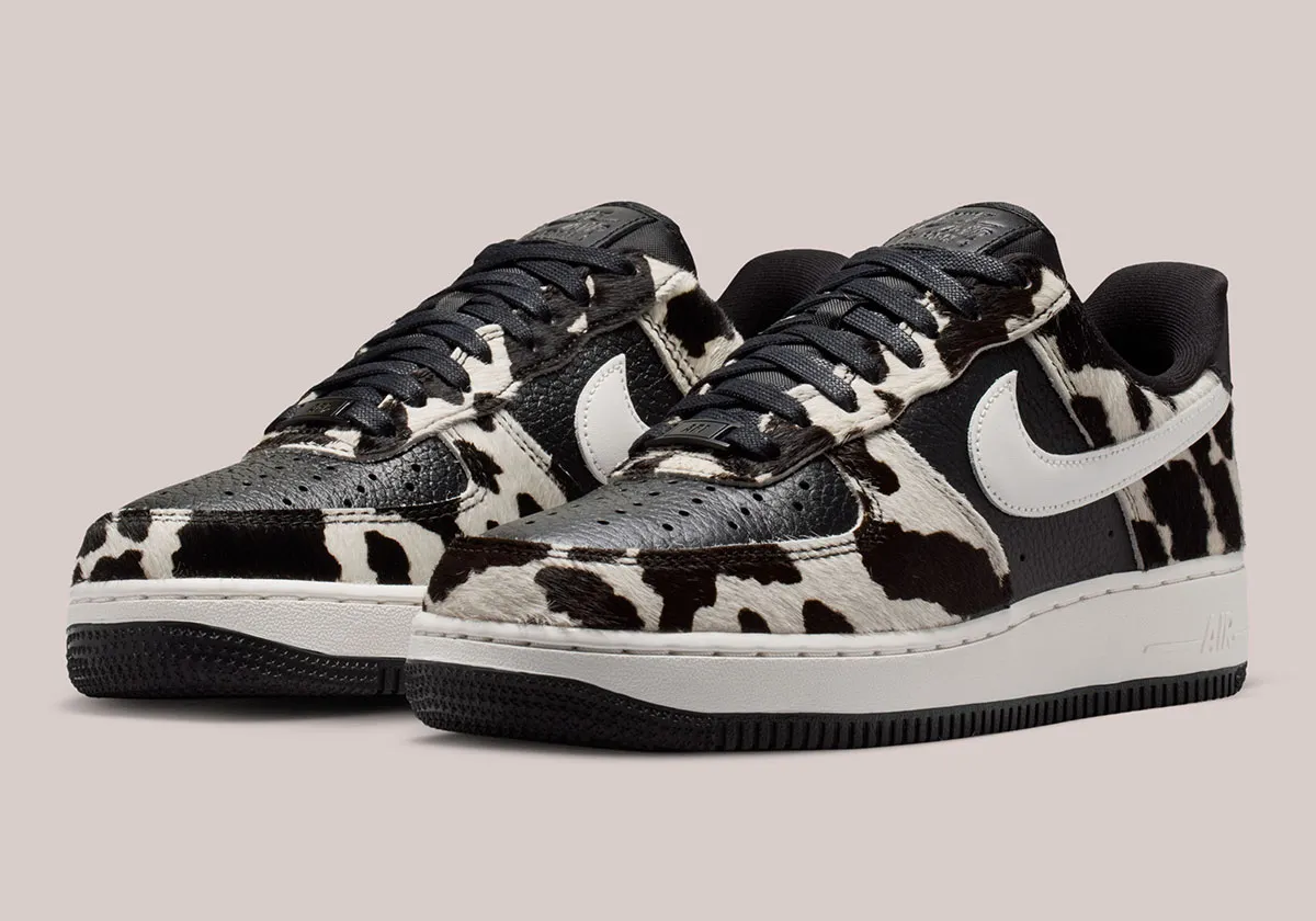 Angled view of Nike Air Force 1 Low “Cow Print” sneakers showing black leather base with textured black-and-white cowhide overlays, white Swoosh, and classic Air sole